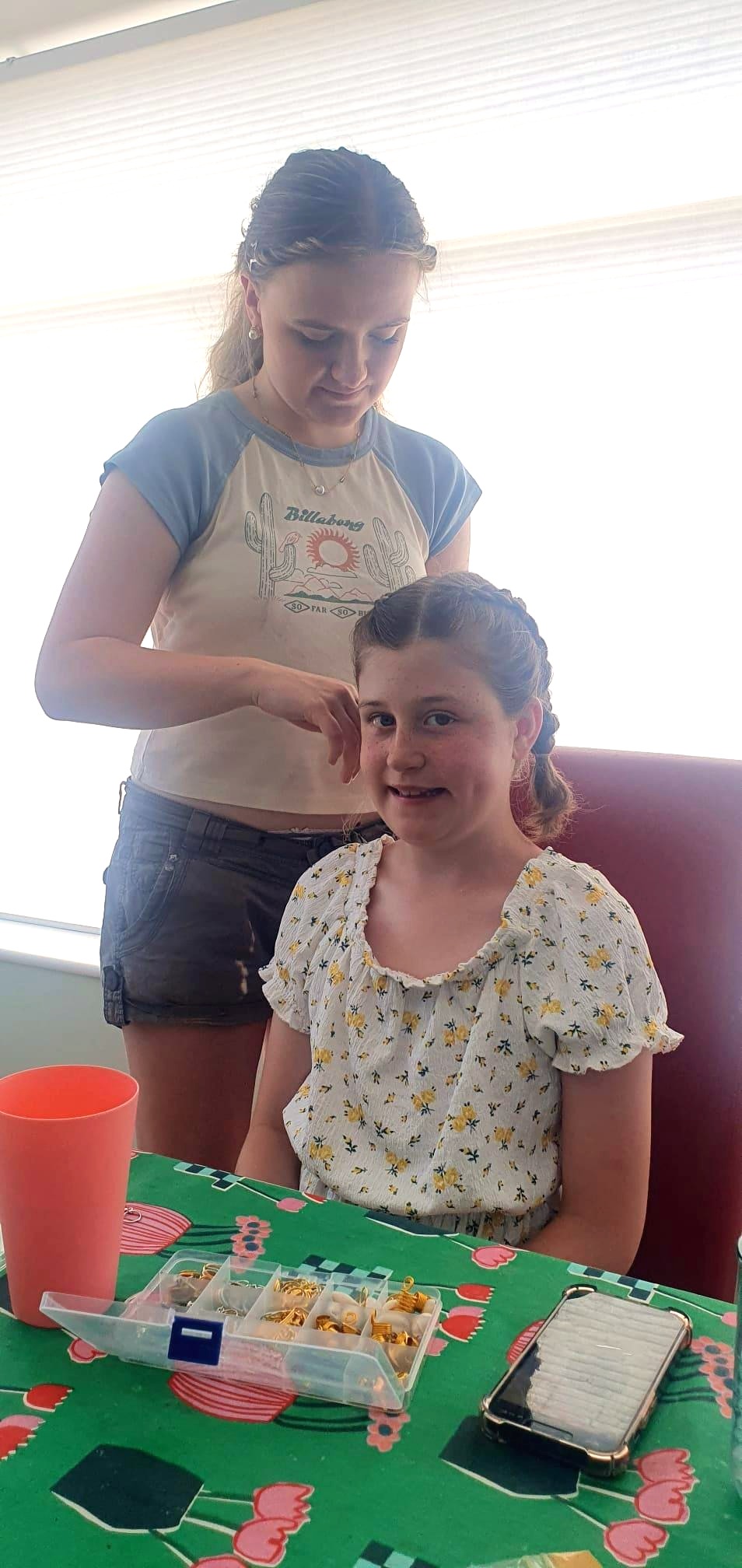 Emma styling a young girl's braids at a birthday party